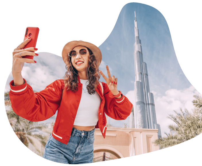 Smiling woman capturing a selfie with Burj Khalifa during a staycation in UAE.