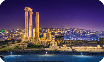 Night view of Roman columns in Amman, Jordan overlooking the city lights.